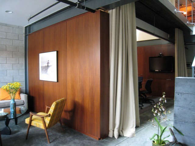  Venture Capital Firm, Venice, California: My client, a venture capital firm based in Boston, leased this loft like space on Abbot Kinney as a branch office. They loved the Southern California openness, but it needed to function as an office. To create privacy as well as warmth I had rich wood veneer wall units made which could fit in below the beams. I chose a heavy linen as interior drapery for accoustical value, also creating privacy when required. Vintage surfing photos were selected to emphasise the California beach location. Photo: Laura Clayton Baker
