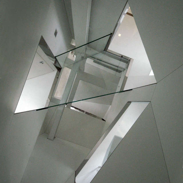  Stairwell_viewed from Attic: The glass floor at Attic level offers a view down through the four-story facetted stairwell,spanned at the third level by a structural glass bridge.