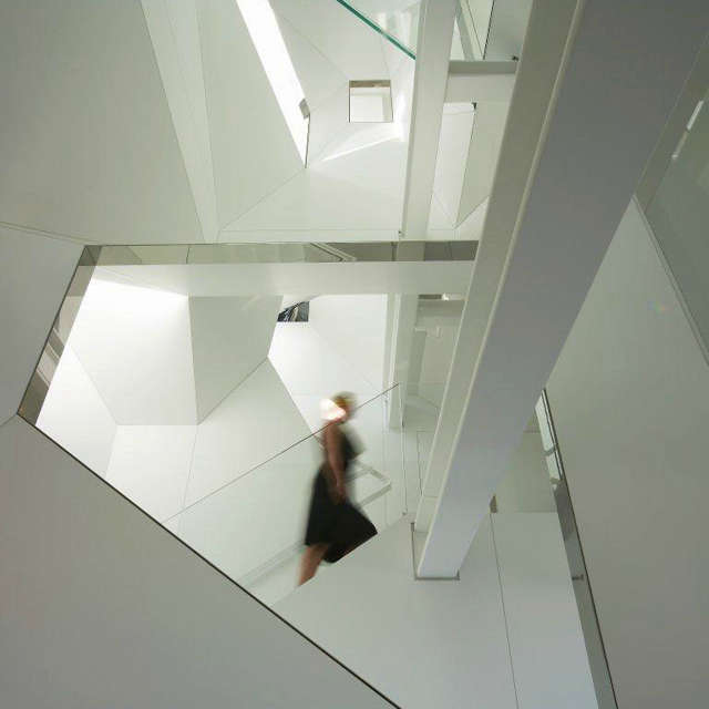  Stairwell_view to Stair: The stair wraps the perimeter of the twisting stairwell and overlooks the stairwell through openings trimmed in mirror polished stainless steel.