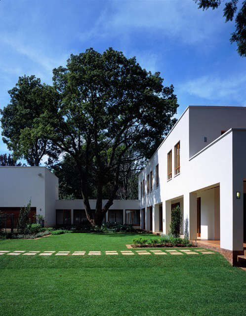  North House, Johannesburg: This courtyard house is designed to wrap around an existing camphor tree. The long colonnade with solid brick piers shades the timber glazing from the sun and provides protection from sudden thunderstorms. To the west, a partially roofed deck creates an outdoor room, over which the branches of an enormous jacaranda tree stretch. Photo: Tristan McLaren