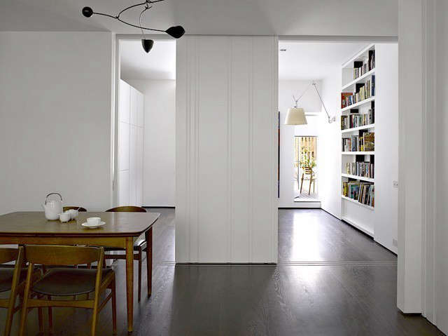  Slide Apartment: A series of white matt lacquer scalloped door panels slide into and out of walls to open and close different spaces, depending on the requirements of the inhabitants. In this photograph, the doors close off the kitchen area from the living/dining room, when required. Photo: Richard Bryant/Arcaid