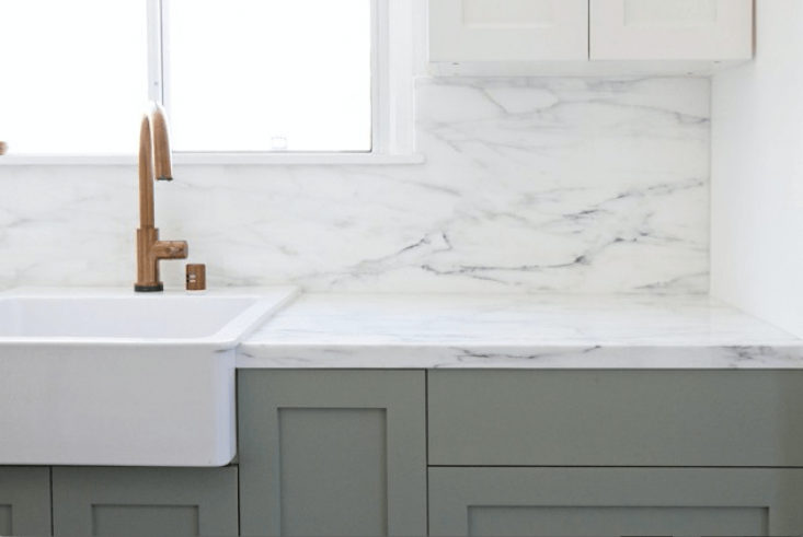 When designing her kitchen, LA-based designer and blogger Sarah Sherman Samuel of Smitten Studio expected to go for Carrara, but discovered “Carrara is generally more gray with smaller veins, and Calacatta is whiter with more dramatic veins. The slab I found was very white and the veins have the prettiest range of colors, including touches of gold and green.” Shown here is the finished product with Calacatta counters and backsplash. See more at SemiHandmade Kitchen with Ikea Cabinets.