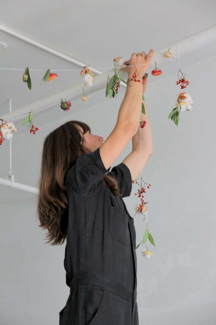 Horvath wraps the garland around exposed pipes in the restaurant.