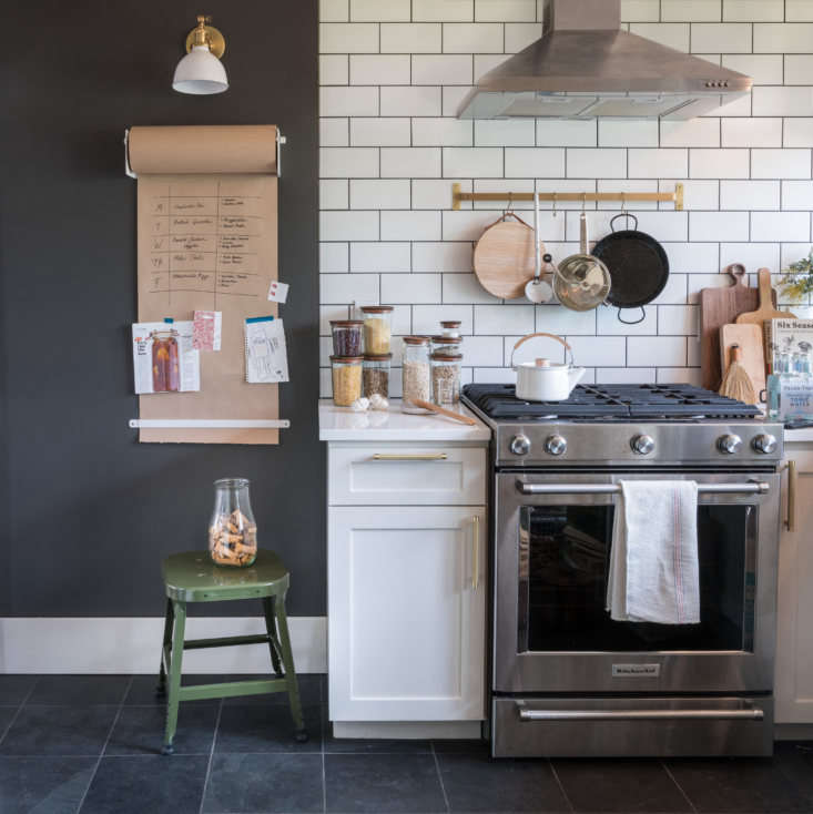 A subway tile kitchen with a Wall-Mounted Paper Holder and brass Utility Rail from Schoolhouse.