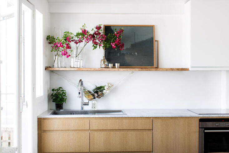 a live edge oak plank serves as an open shelf, which antoine styles with glass  19