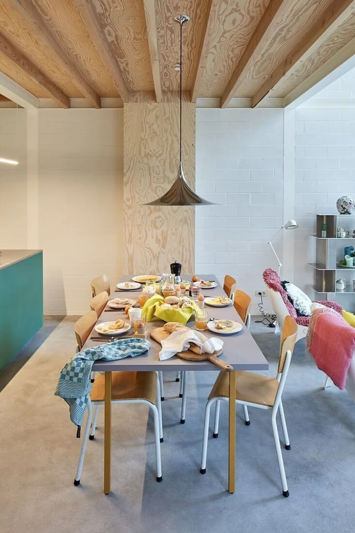 a classic gubi semi pendant hangs over the dining table surrounded by some of e 21