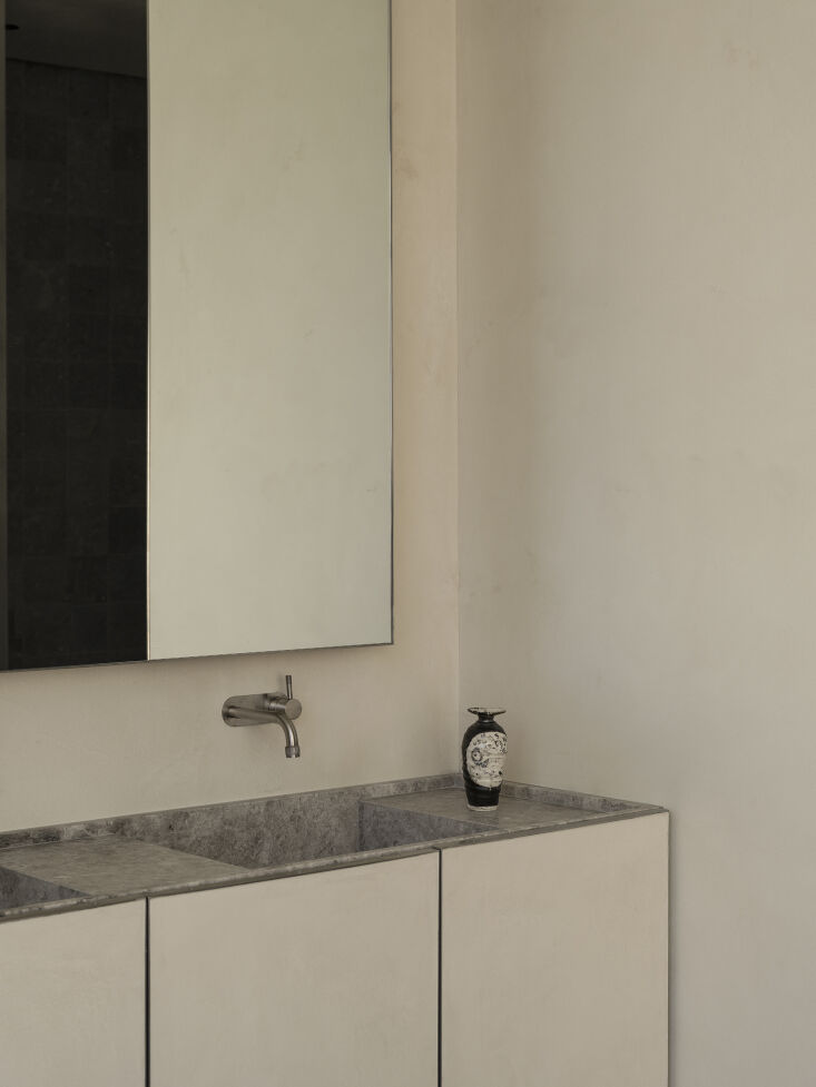 a bathroom designed with custom limestone slab wash basins and a brodware bathr 32