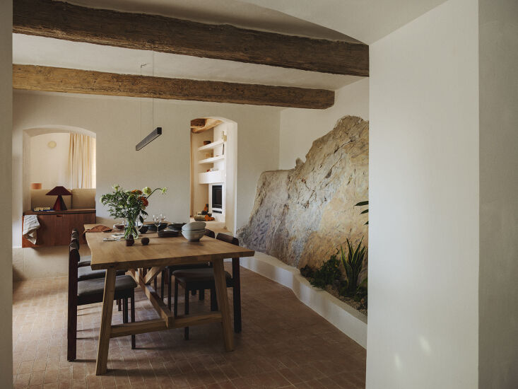 Una mesa de comedor de granja corre paralela a la piedra vista de la ladera. veintiuno