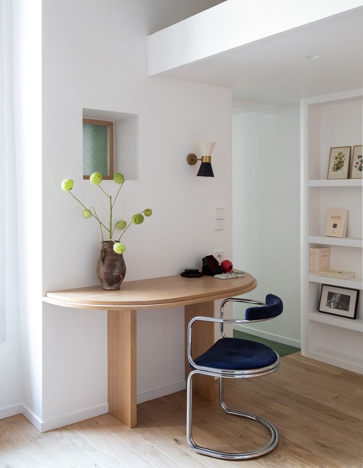 a half circle desk in oak is built into the wall and paired with a vintage chai 22