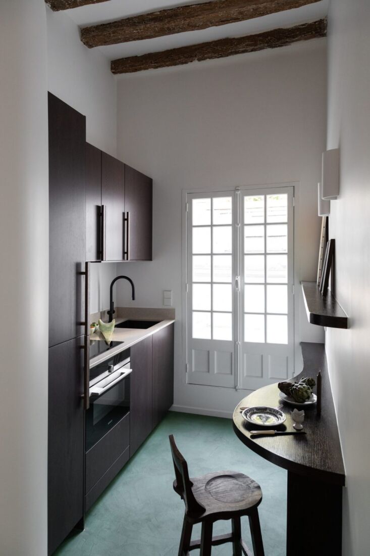 a french door opens into a pocket sized kitchen with a colored concrete floor a 17