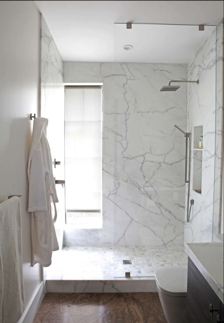 In the same Sonoma house, a narrow, water-resistant roller shade is tucked into a window recess in the marble shower. Photograph by Karen Steffens for Remodelista.