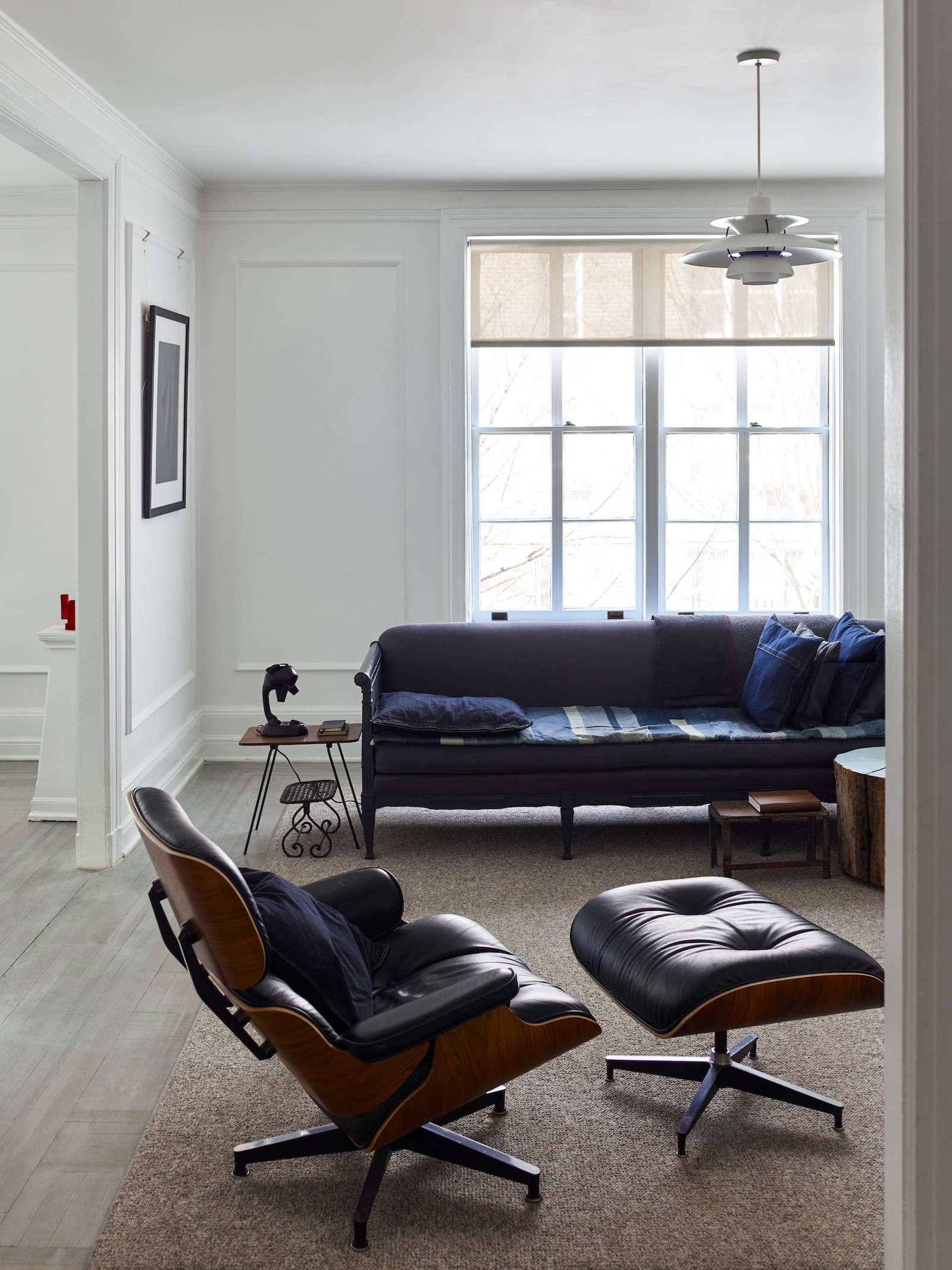 an eames armchair and vintage sofa are softened with throw pillows and a folded 10