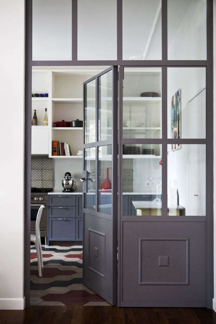 a custom iron and glass door divides kitchen from living area in this rome proj 13