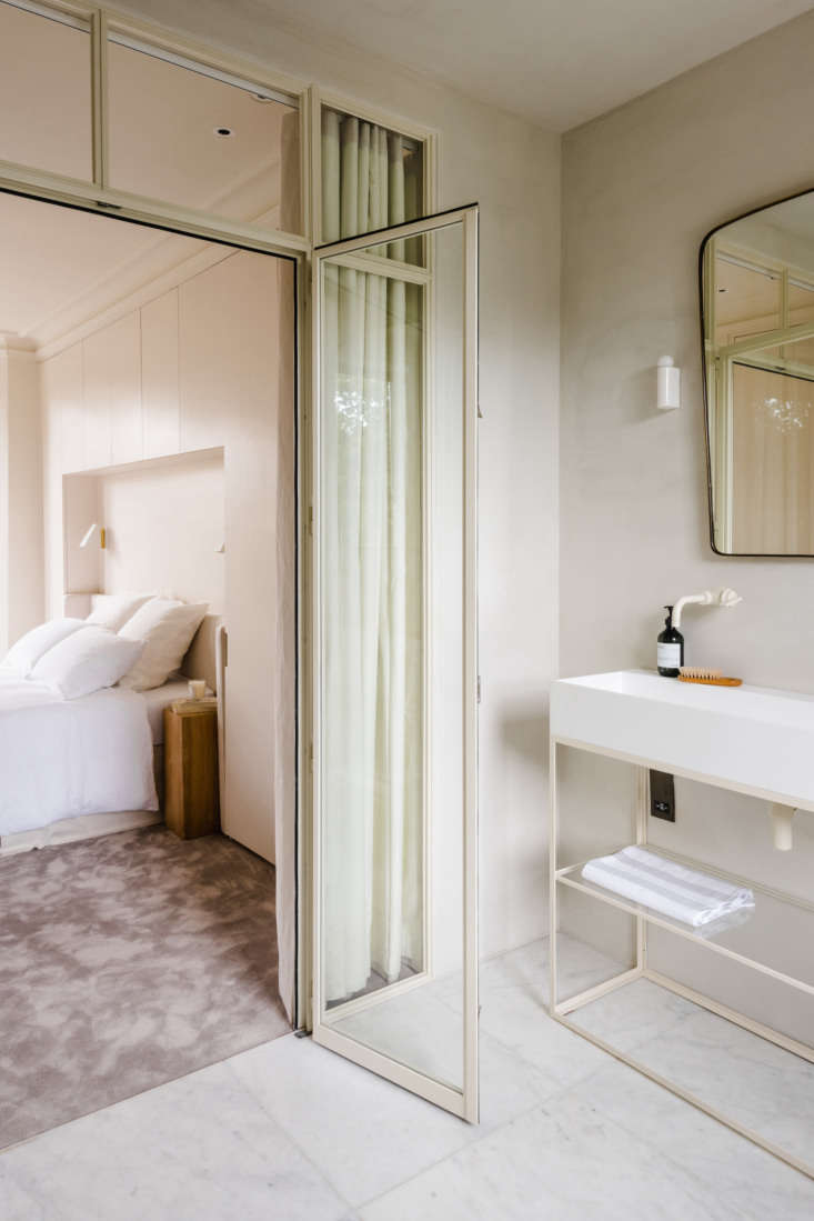 a crittall steel and glass door separates the bedroom from the ensuite bath. &a 9
