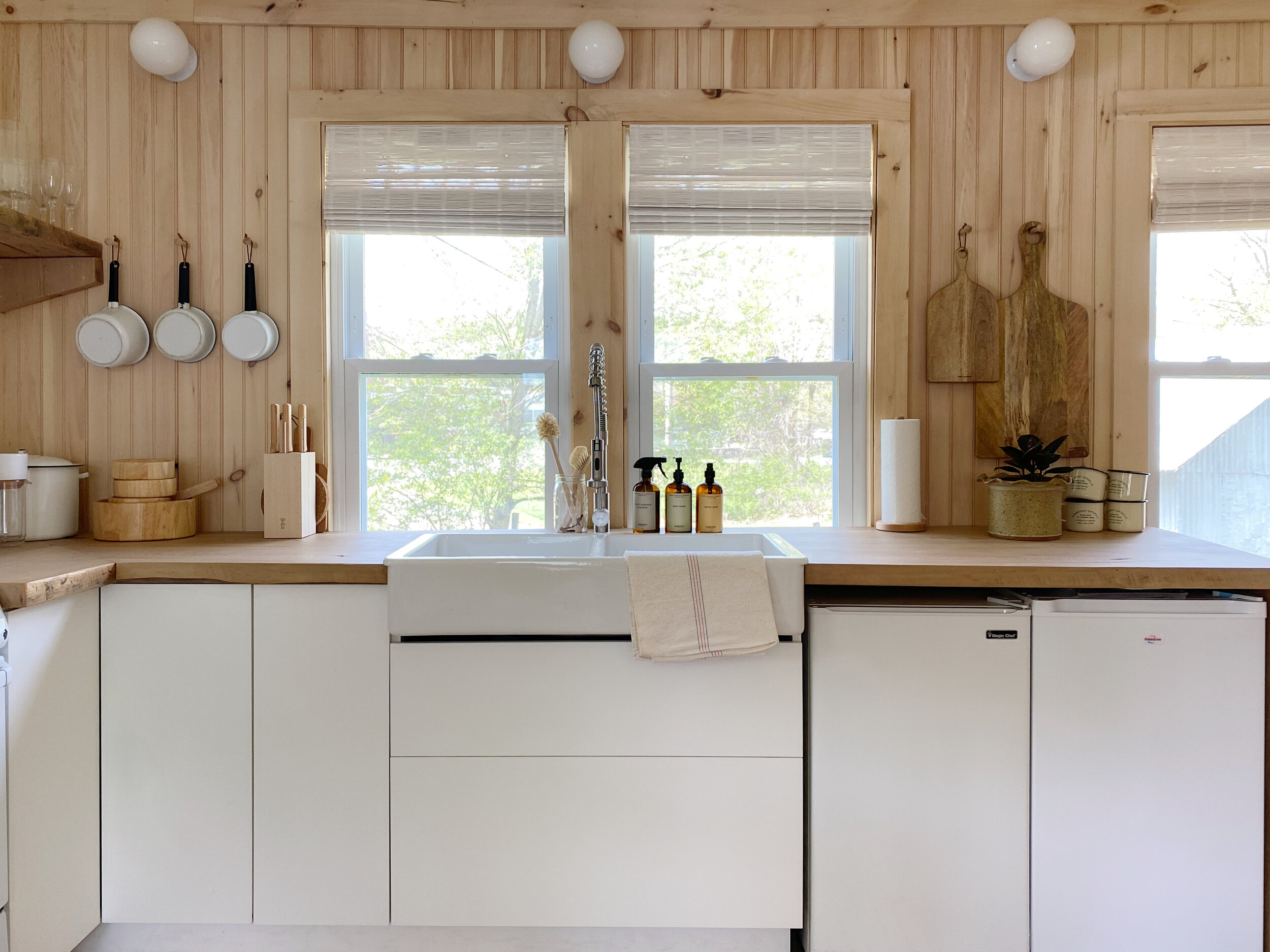 the kitchen is designed with plain white lower cabinets, reclaimed wood counter 9