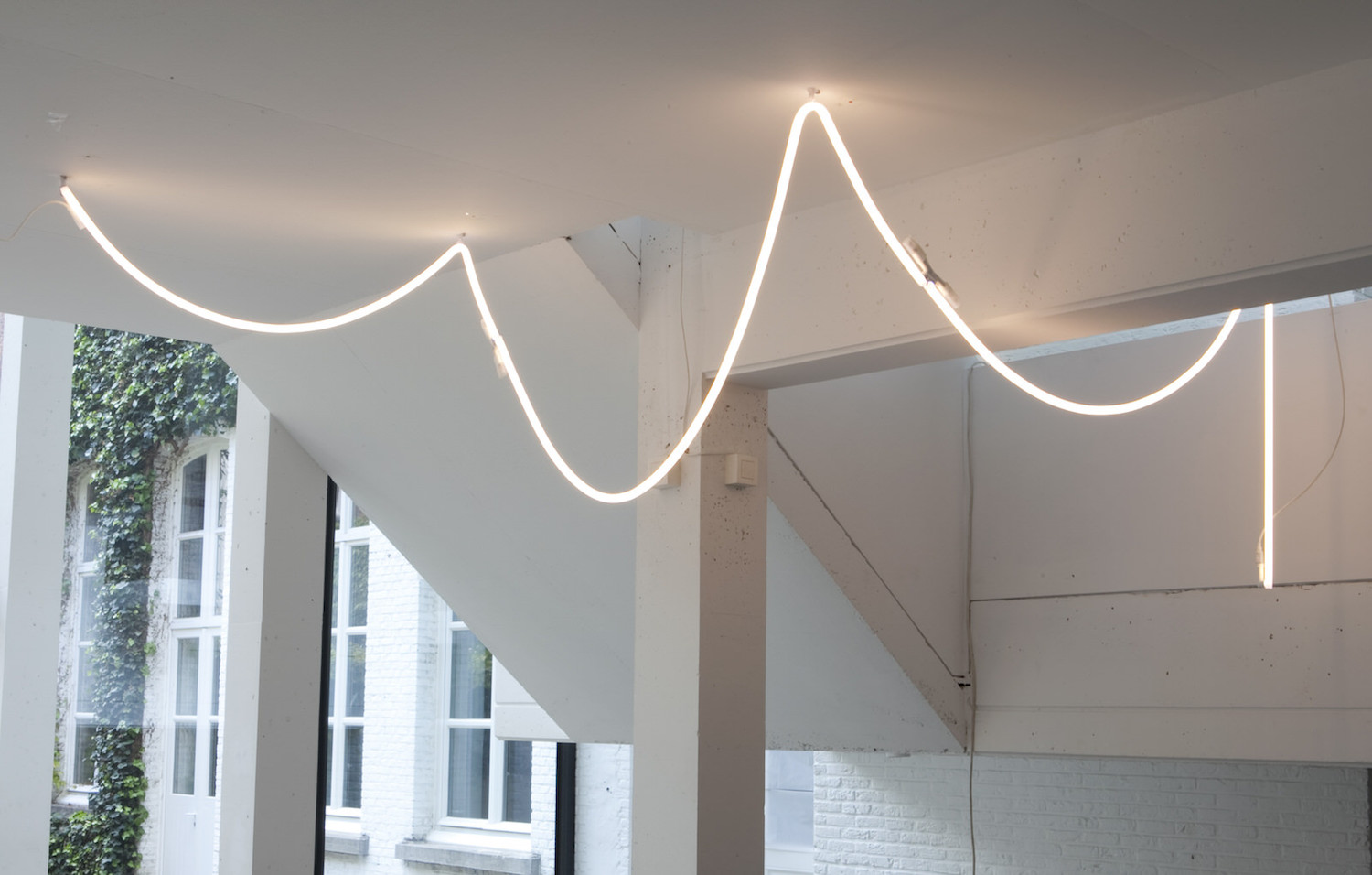 the hanging lamp layered with the track lighting is the muller van severen neon 14