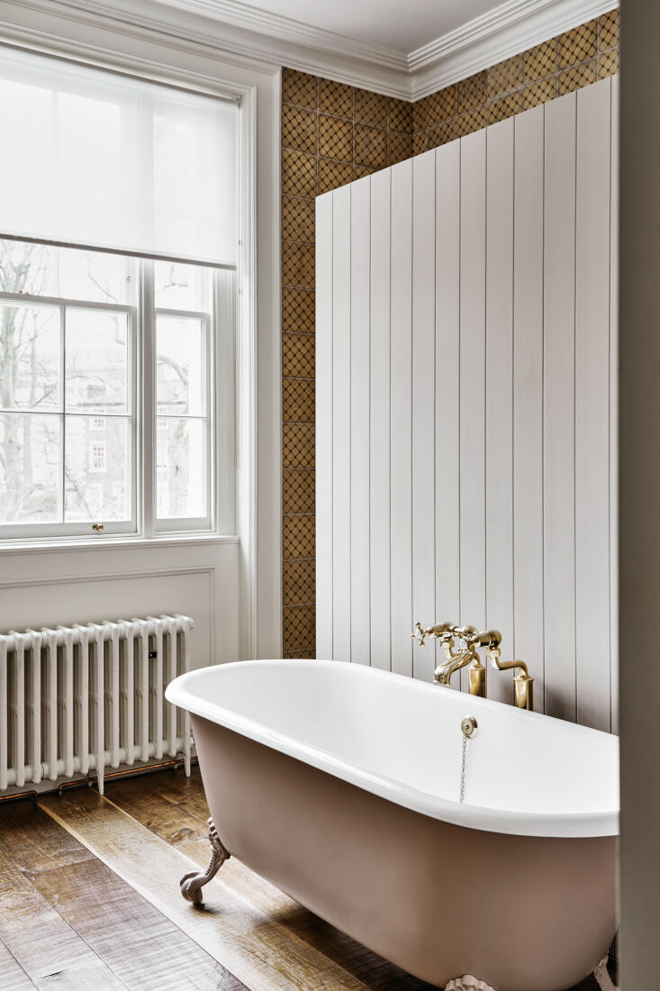 a paneled divider sets off a clawfoot bathtub from drummonds, another uk compan 29