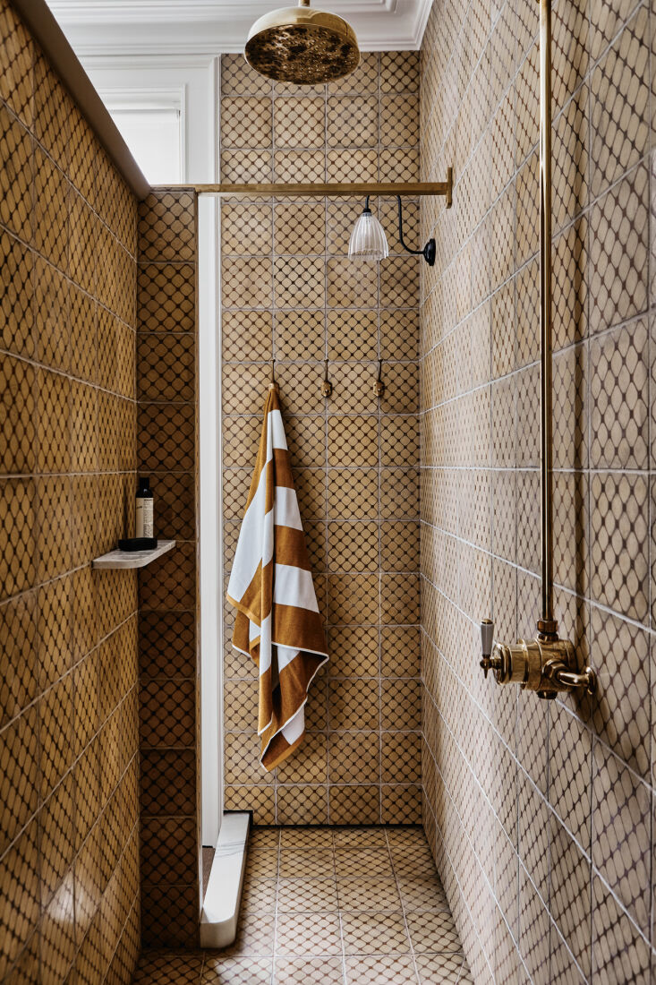 the shower has a carrara marble step and shelves. the brass shower fixture is f 30