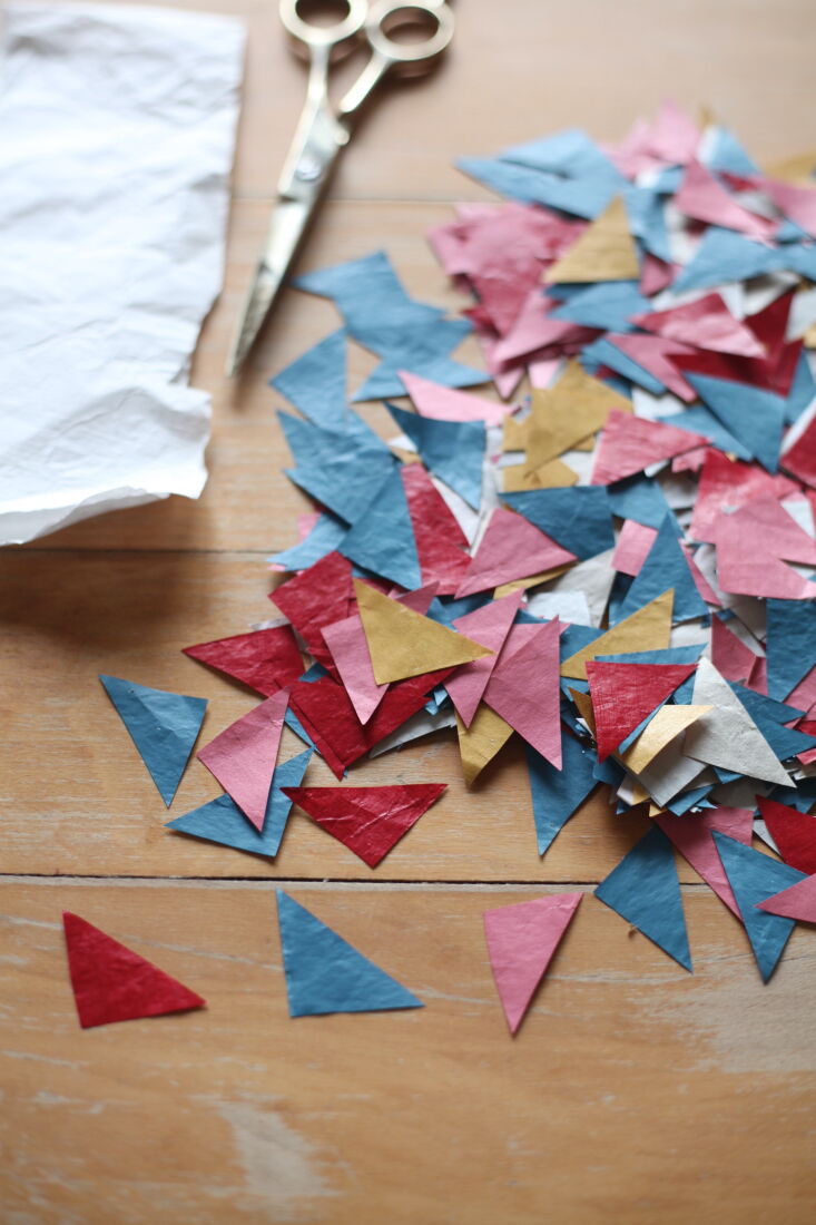 next, she cuts the paper into geometric shapes. she applies glue—akin to 15