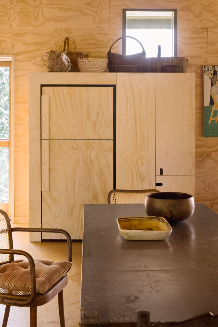 a repurposed refrigerator is encased in plywood, pulls included, and built into 10