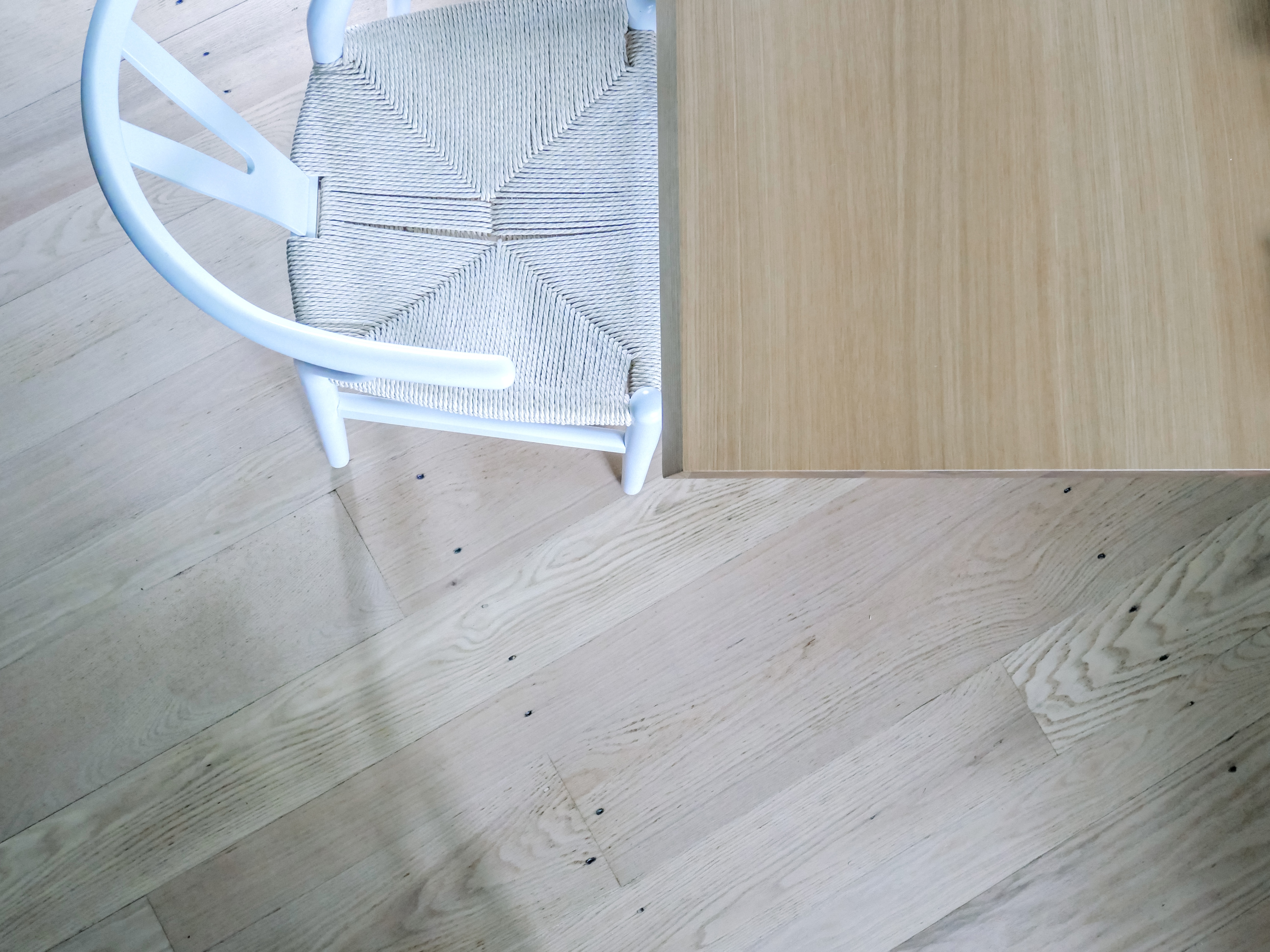 detail of oak floors with bludot walk in the park white oak dining table and poly bark wishbone chair