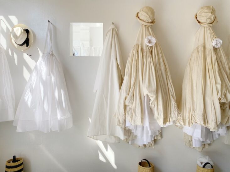 cotton and silk garments hang on a sun dappled wall. 18