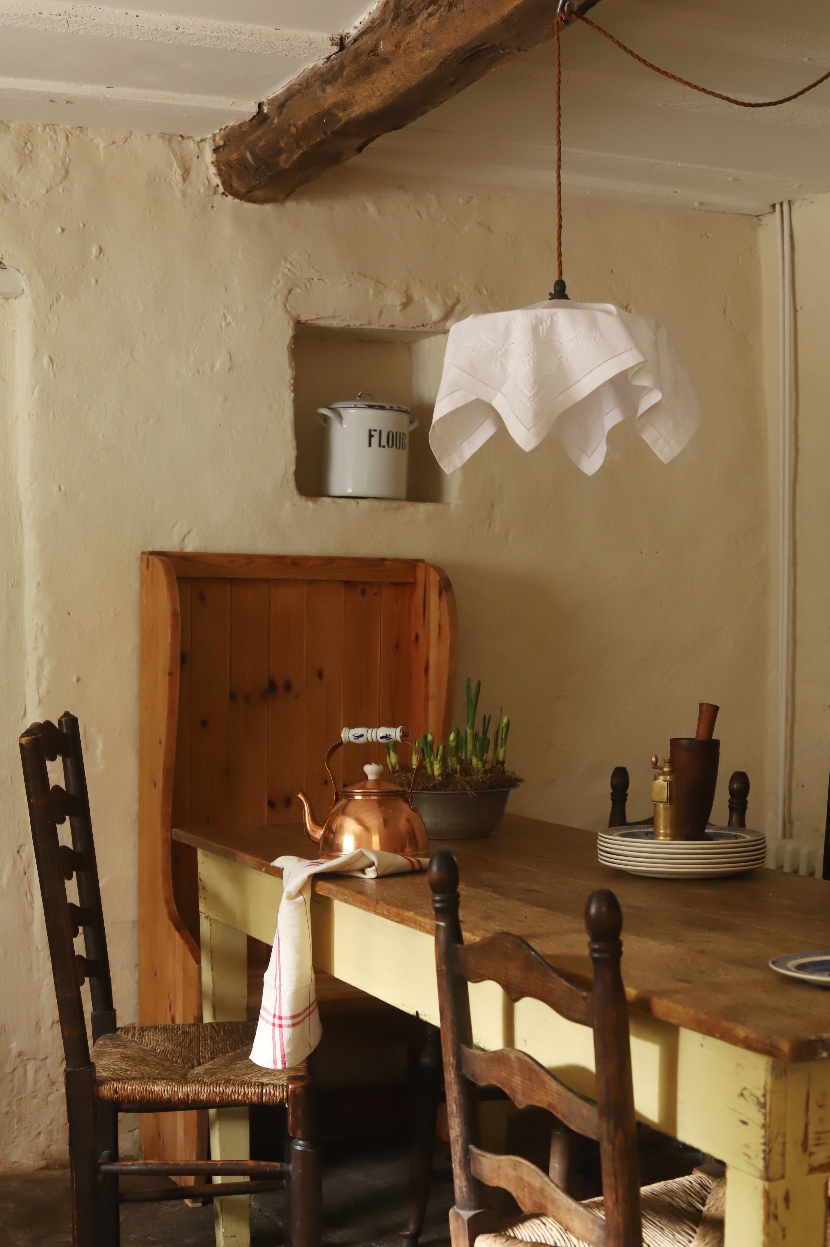 an old farmhouse table is surrounded by ladder back chairs. admiring the linen  16