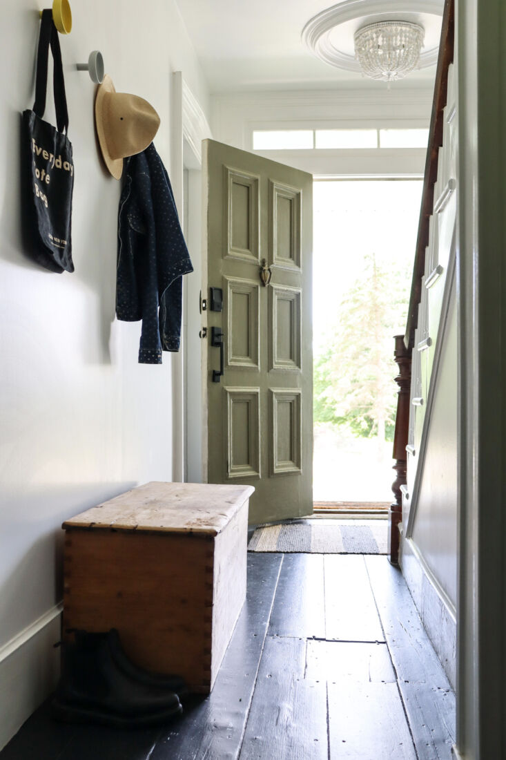 the entry, like the rest of the house, has painted wood floors—a custom  15
