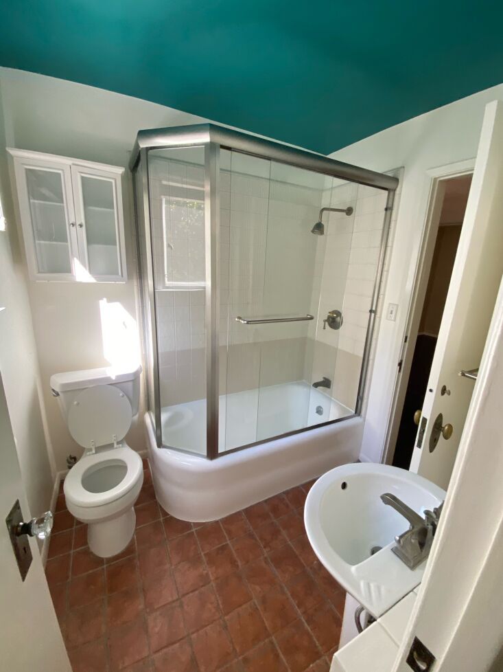 the compact bathroom had a teal ceiling, square terracotta floor tiles, and tir 26