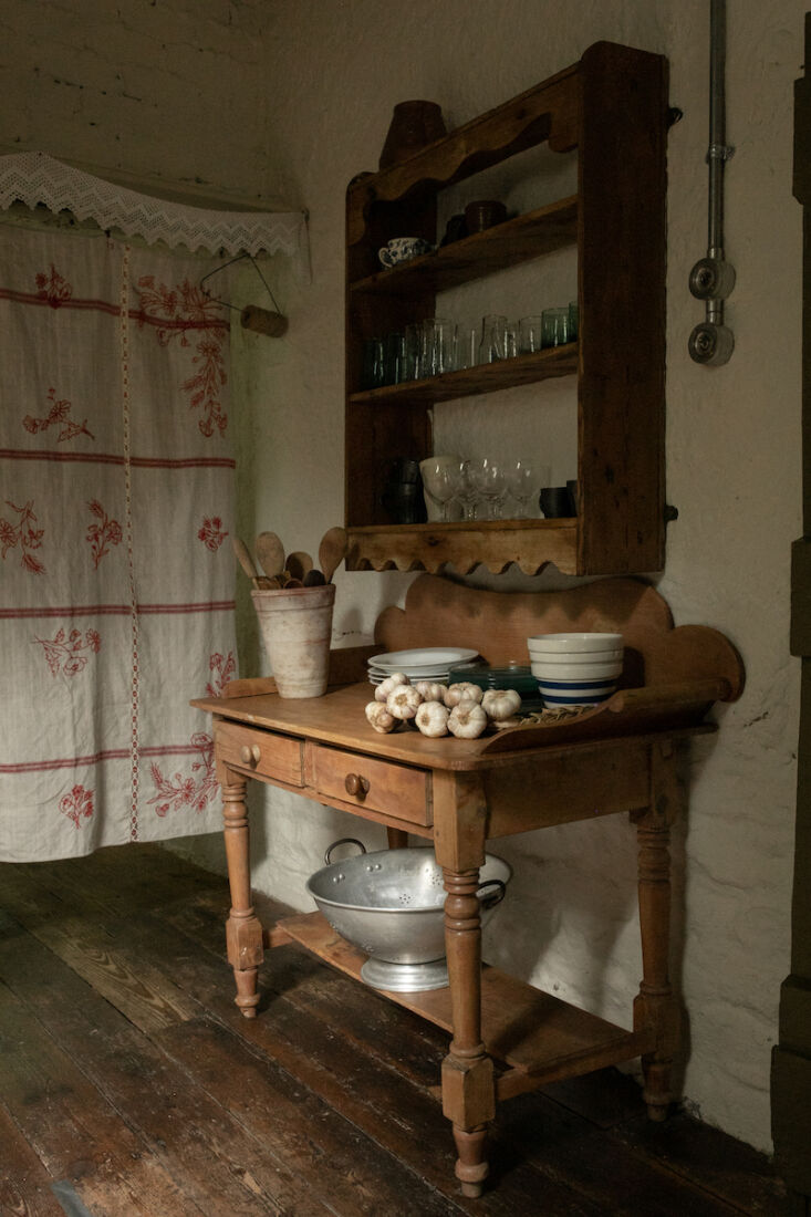 the kitchen is separated from the hallway by an antique piece of embroidered li 16