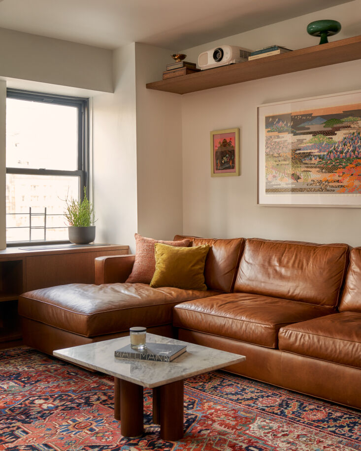 a projector is smartly nestled on a floating shelf above the camel leather sofa 13