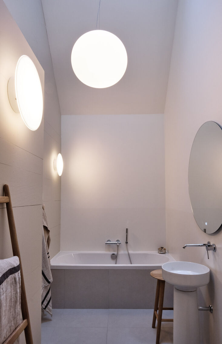 a pair of aj eklipta wall lamps illuminate the bathroom along with a flos glo b 36