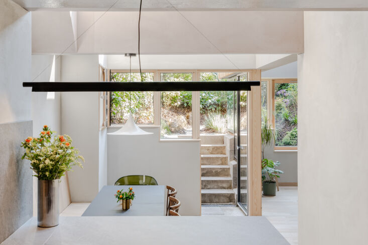 the gubi semi pendant in white hangs over the dining table. 20