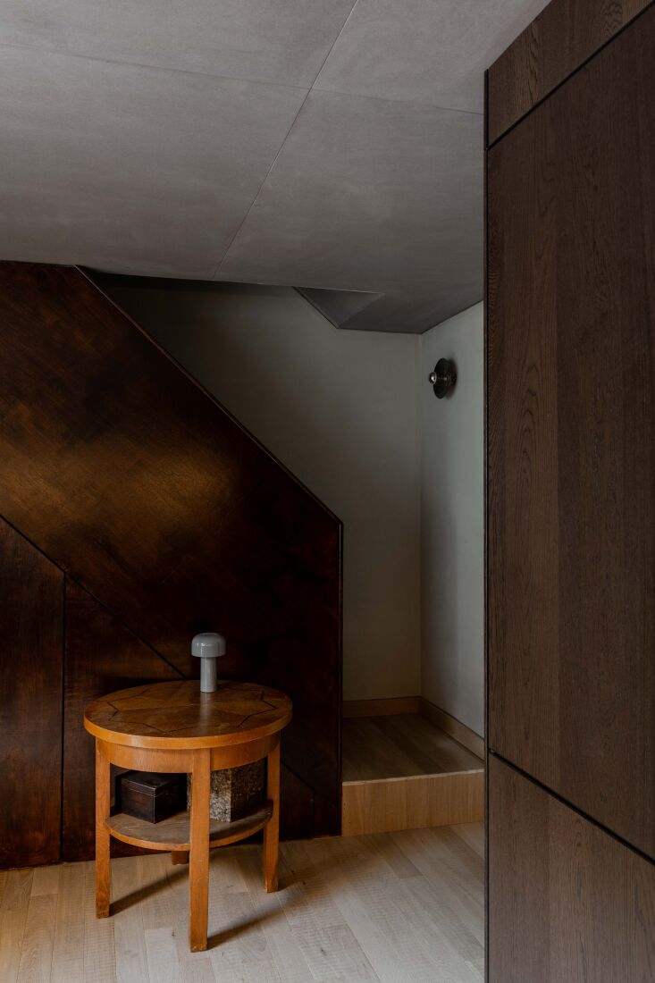 a dark wood stairwell and grey toned limewash walls. the side table is lit with 25