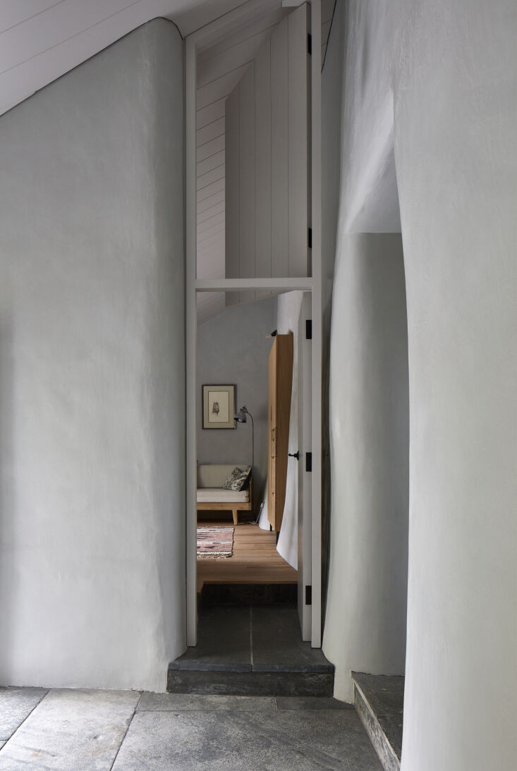 a rounded plaster entryway fitted with a modern door opens into a downstairs be 26