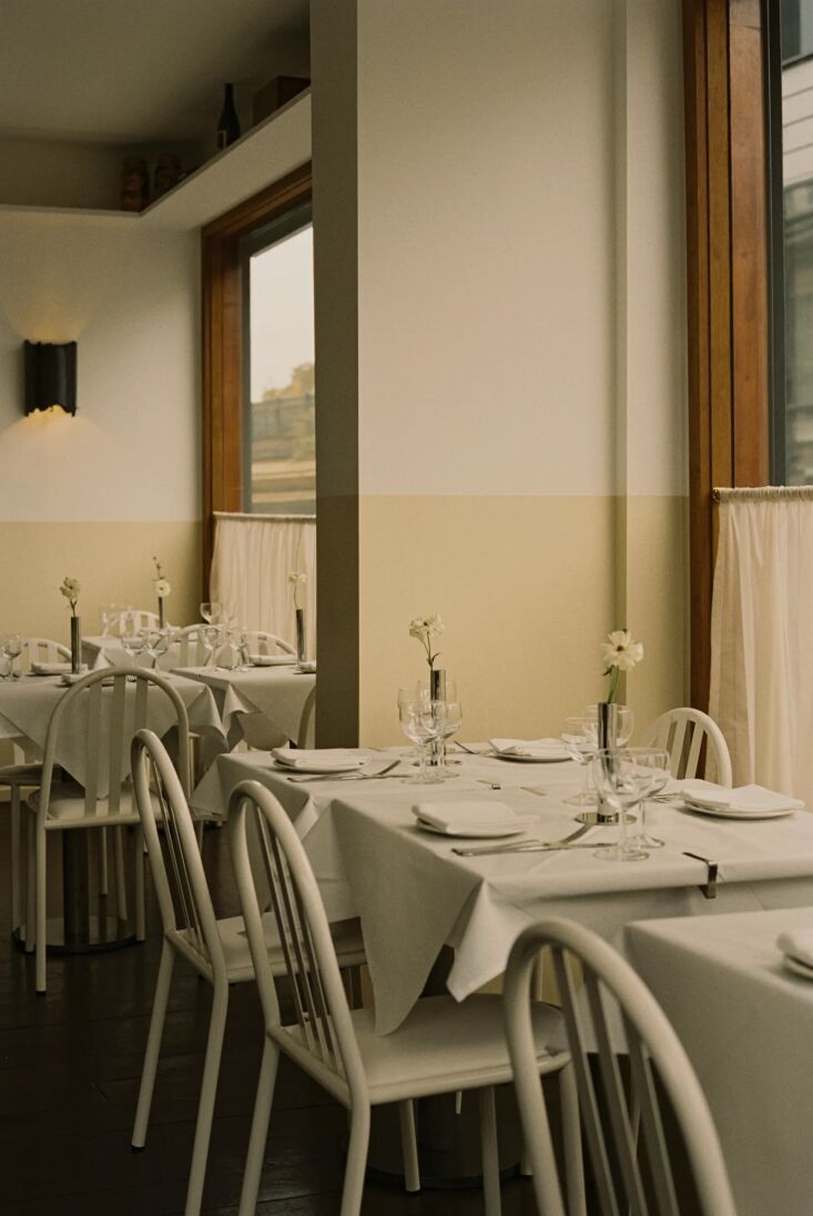 Las paredes son de tonos blancos y crema y cada ventana tiene cortinas color café. 18