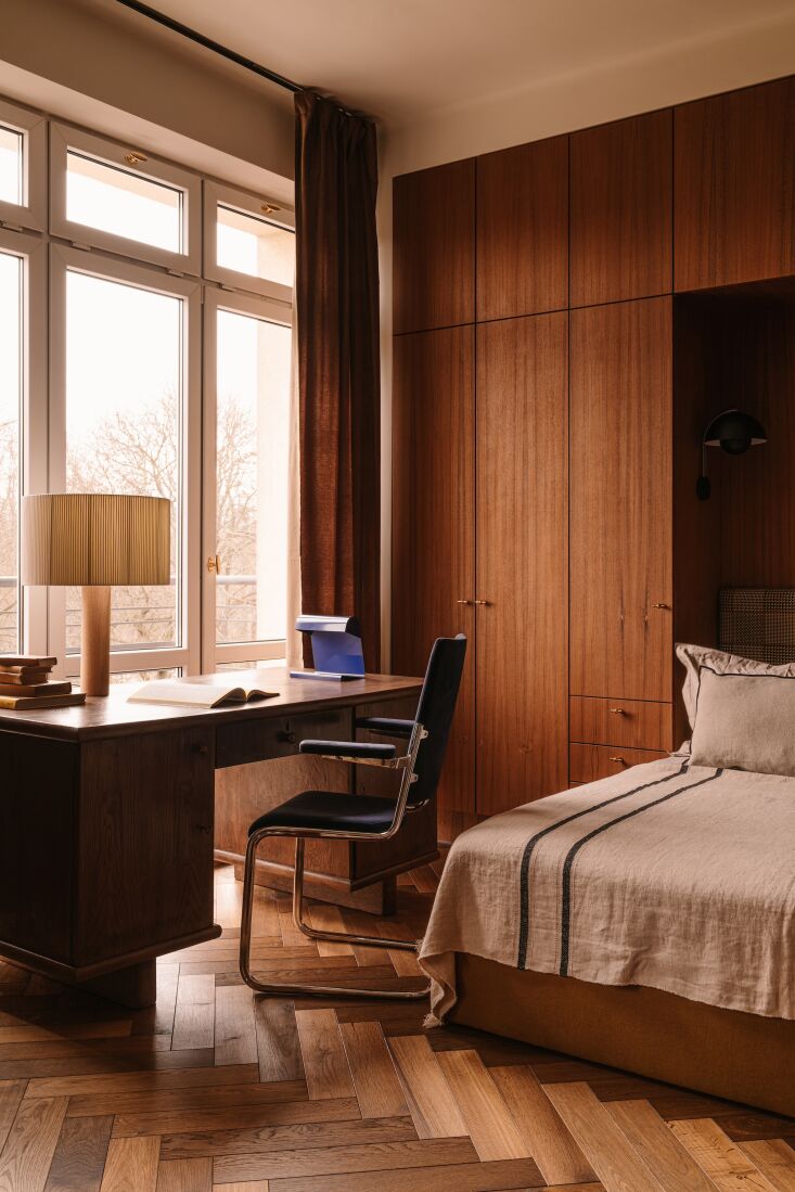 a blue lampe de bureau, designed by jean prouvé, sits atop a vintage desk. 26