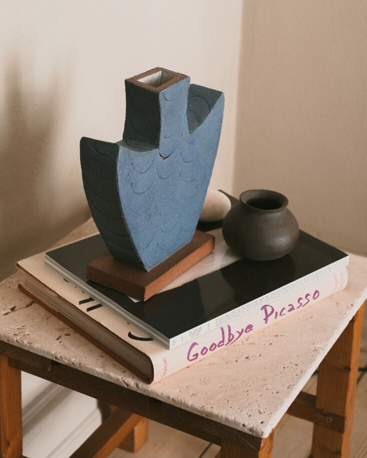 a sculpture, the blue angel, by shane gabier, sits on a stack of reference book 24