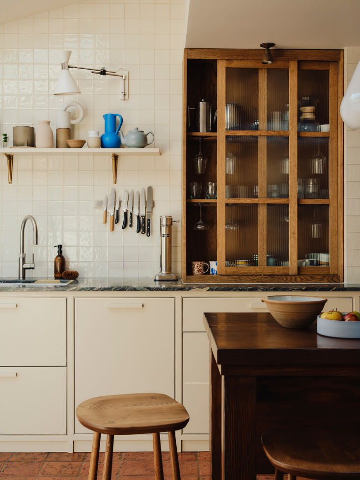terracotta floors, a custom made dark wood island, a wood hutch, and stools by  20